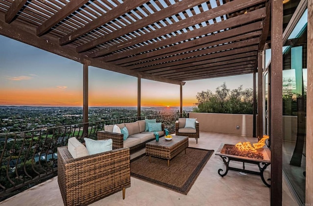 patio terrace at dusk with an outdoor living space with a fire pit and a pergola