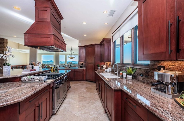 kitchen featuring sink, range with two ovens, island range hood, light stone countertops, and decorative backsplash