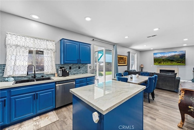 kitchen with blue cabinets, a kitchen island, a sink, light countertops, and dishwasher