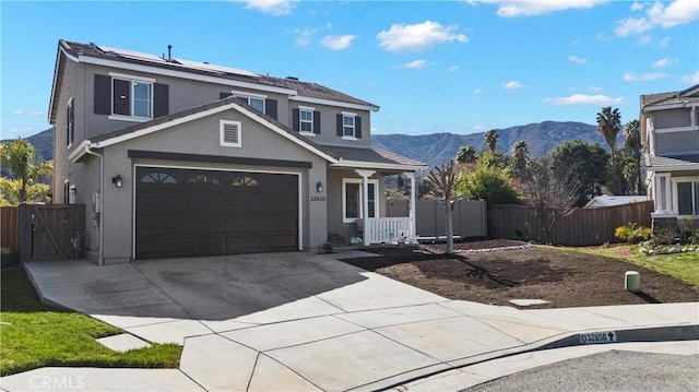 traditional home with a mountain view, a garage, fence, concrete driveway, and stucco siding