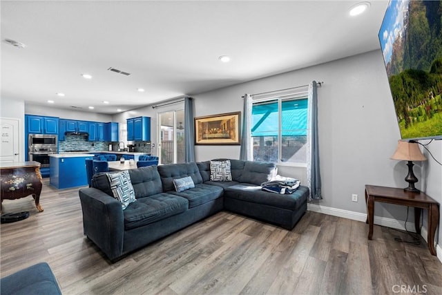 living room with baseboards, recessed lighting, visible vents, and light wood-style floors