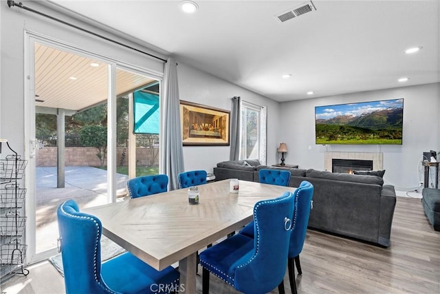 dining area with light wood-style floors, a fireplace, visible vents, and a wealth of natural light