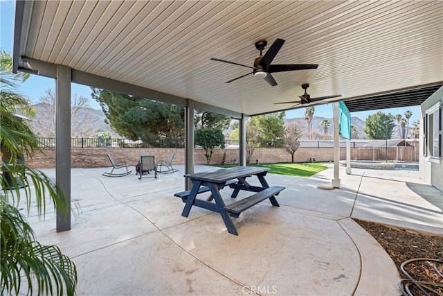 view of patio / terrace featuring ceiling fan, outdoor dining area, a fenced backyard, and a mountain view