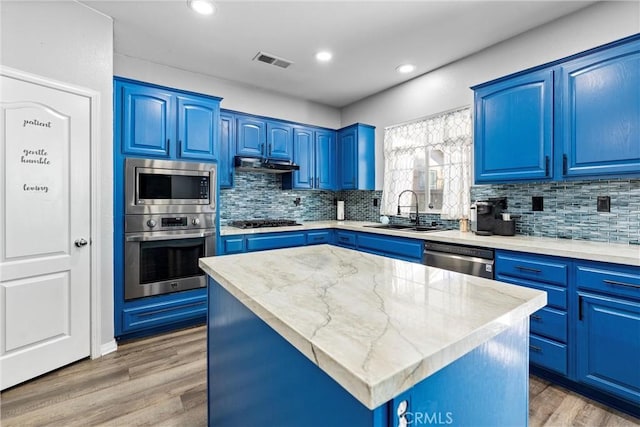 kitchen featuring stainless steel appliances, blue cabinetry, visible vents, and a center island