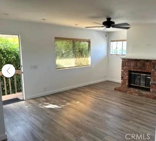 unfurnished living room featuring hardwood / wood-style flooring, ceiling fan, and a fireplace