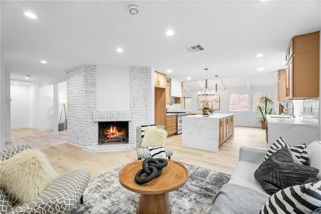 living room featuring lofted ceiling, light wood-type flooring, and a brick fireplace