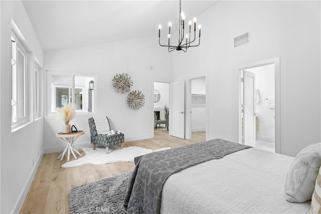 bedroom with ensuite bathroom, a spacious closet, high vaulted ceiling, light wood-type flooring, and a fireplace