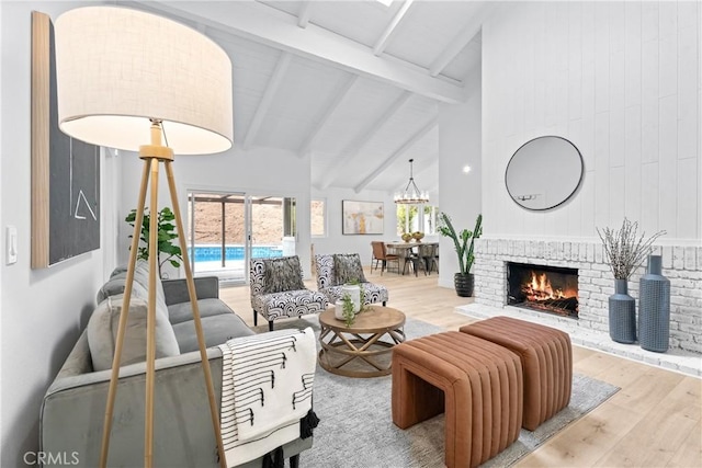 living room with hardwood / wood-style flooring, an inviting chandelier, beam ceiling, high vaulted ceiling, and a fireplace