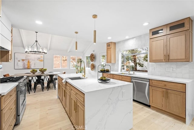 kitchen with a healthy amount of sunlight, vaulted ceiling with beams, an island with sink, appliances with stainless steel finishes, and a sink