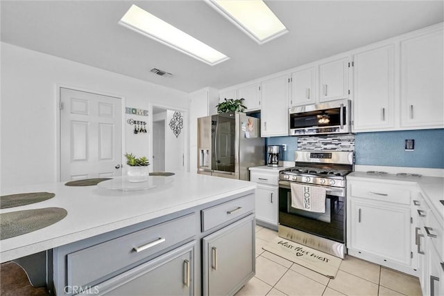 kitchen with white cabinetry, stainless steel appliances, backsplash, and light tile patterned floors