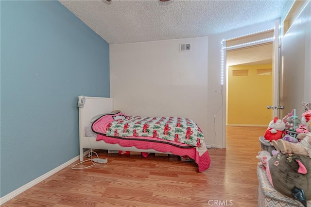 bedroom with light hardwood / wood-style floors and a textured ceiling