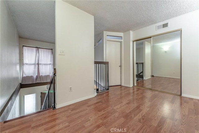 unfurnished room with hardwood / wood-style floors and a textured ceiling