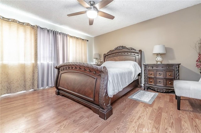 bedroom with hardwood / wood-style floors, a textured ceiling, and ceiling fan