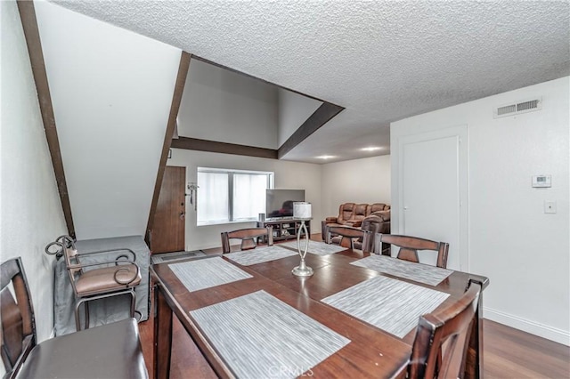 dining room with wood-type flooring and a textured ceiling