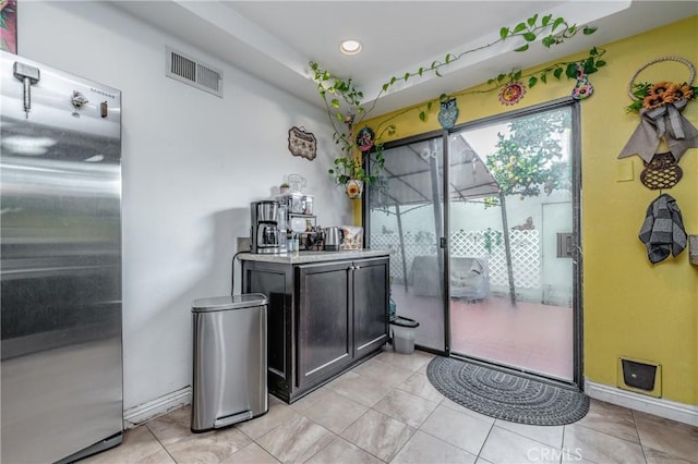 bar with stainless steel refrigerator and light tile patterned flooring