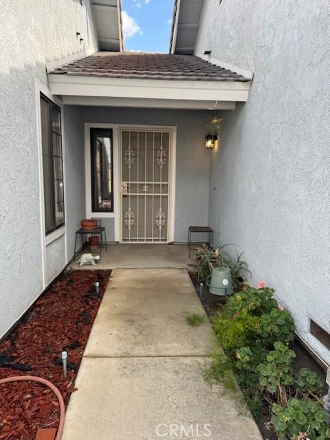 view of exterior entry featuring a shingled roof and stucco siding