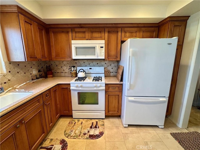 kitchen with tasteful backsplash, sink, light tile patterned floors, and white appliances