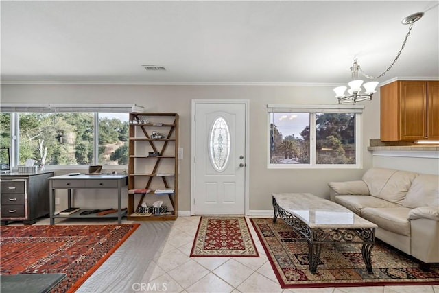 foyer entrance with ornamental molding, light tile patterned floors, and an inviting chandelier