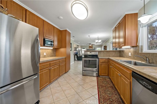 kitchen featuring sink, decorative light fixtures, light tile patterned floors, appliances with stainless steel finishes, and kitchen peninsula