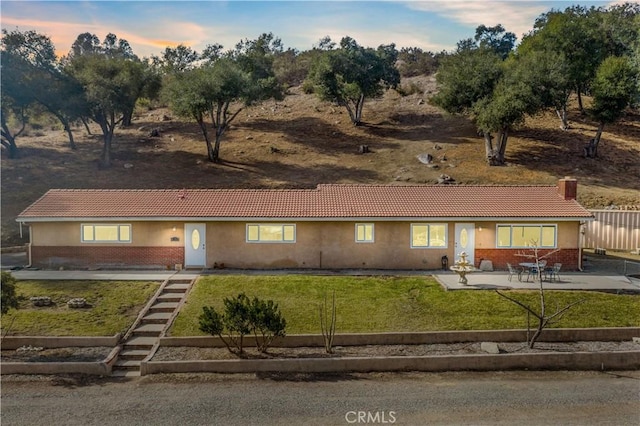 view of front of home with a patio and a lawn