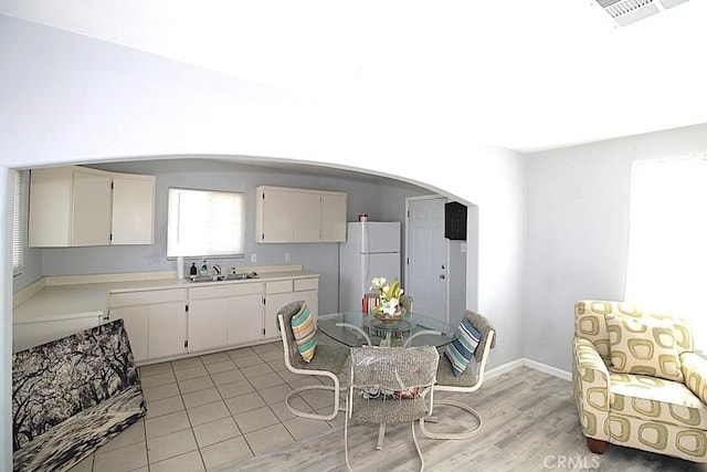 kitchen with light wood-type flooring, white refrigerator, white cabinetry, and sink