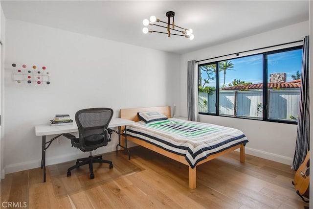 bedroom with an inviting chandelier and light wood-type flooring