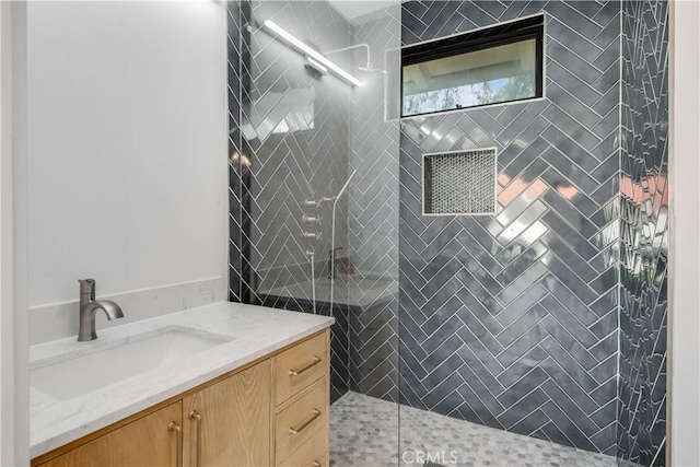 bathroom with tiled shower and vanity