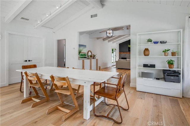 dining room featuring lofted ceiling with beams and light wood-type flooring