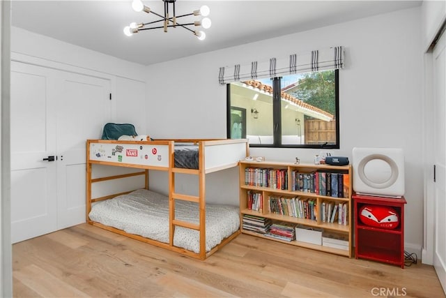 bedroom featuring an inviting chandelier, wood-type flooring, and a closet