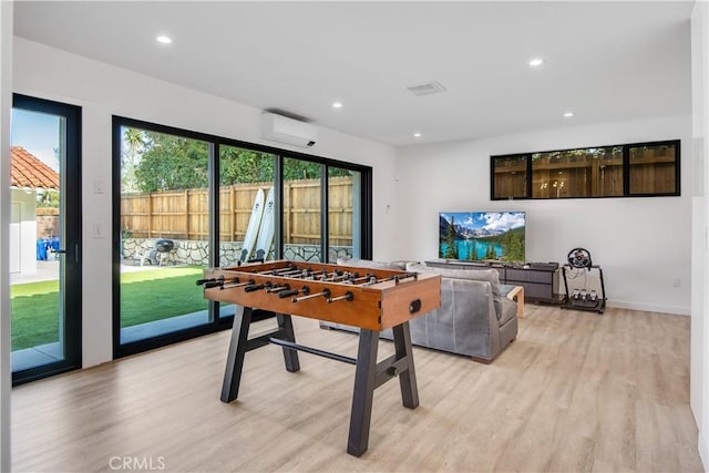 playroom with light hardwood / wood-style flooring and a wall mounted AC