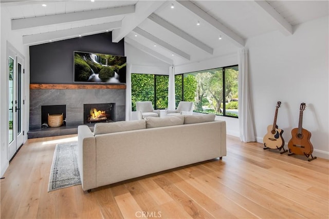 living room featuring a premium fireplace, lofted ceiling with beams, and light wood-type flooring