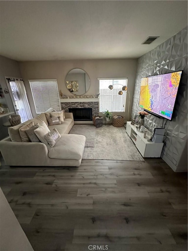 living room featuring hardwood / wood-style flooring, a stone fireplace, and a wealth of natural light