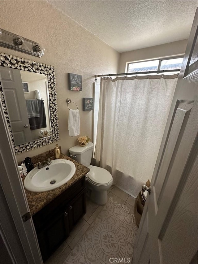 bathroom with vanity, toilet, tile patterned flooring, and a textured ceiling