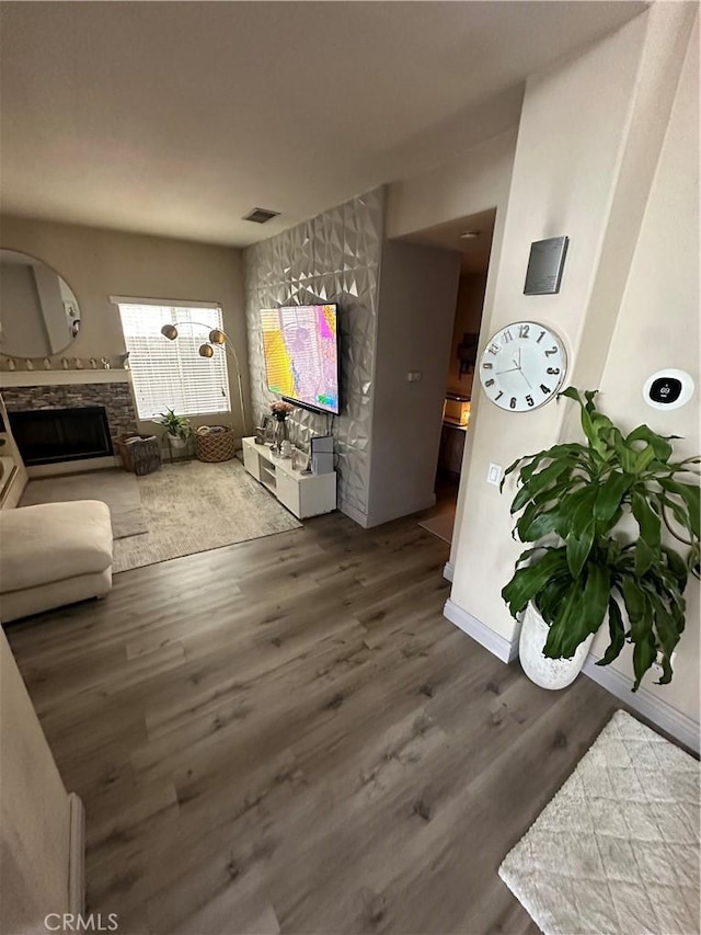 living room with hardwood / wood-style floors and a stone fireplace