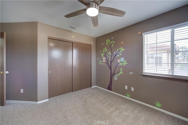 unfurnished bedroom featuring ceiling fan, light colored carpet, and a closet