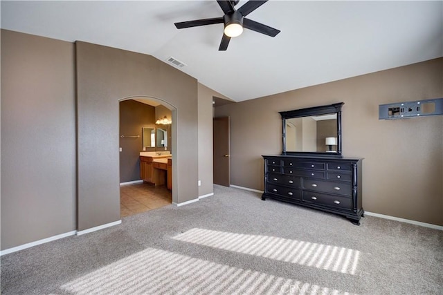 unfurnished bedroom featuring ensuite bathroom, lofted ceiling, light carpet, and ceiling fan