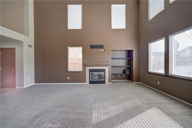 unfurnished living room featuring a high ceiling, light carpet, and a fireplace