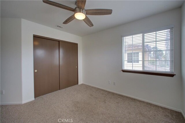 unfurnished bedroom featuring ceiling fan, visible vents, carpet floors, baseboards, and a closet