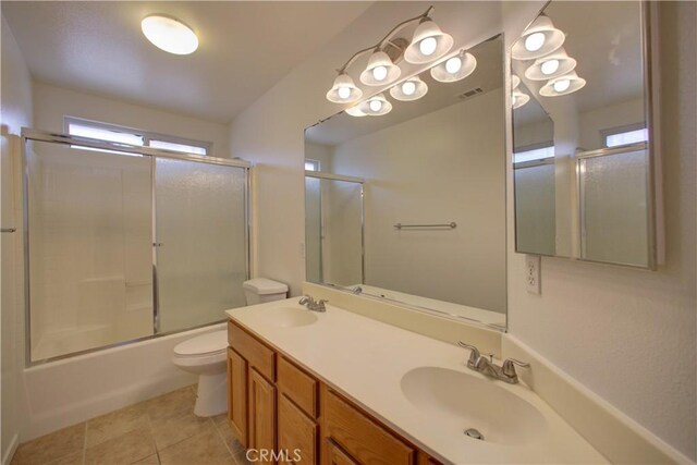 bathroom with a sink, tile patterned flooring, toilet, and double vanity