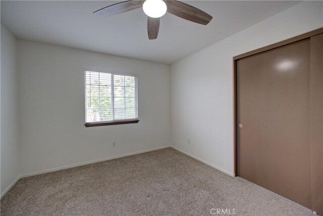 unfurnished bedroom with a closet, baseboards, ceiling fan, and carpet flooring