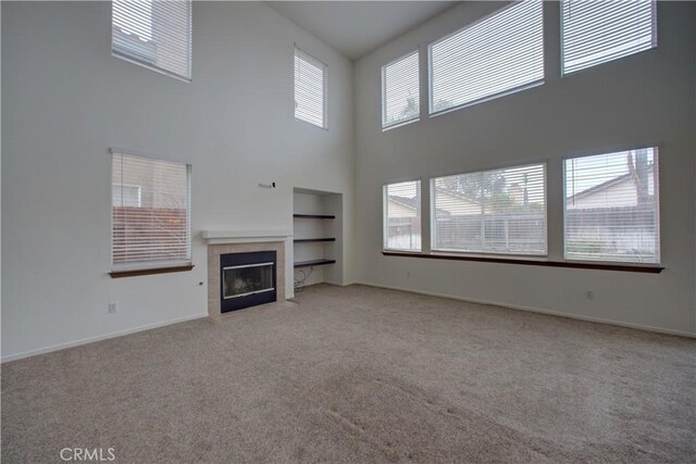 unfurnished living room featuring baseboards, carpet, a high ceiling, and a fireplace