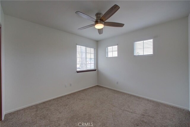 spare room with baseboards, carpet, and a ceiling fan