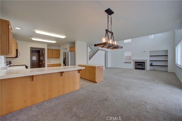 kitchen with a kitchen breakfast bar, tile countertops, stainless steel refrigerator with ice dispenser, light colored carpet, and a peninsula
