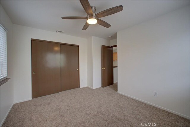 unfurnished bedroom featuring multiple windows, visible vents, baseboards, a closet, and carpet