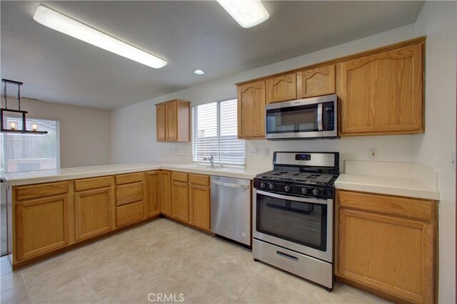 kitchen featuring tile countertops, a sink, a peninsula, stainless steel appliances, and recessed lighting