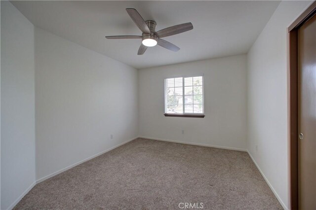 spare room featuring carpet floors, baseboards, and ceiling fan
