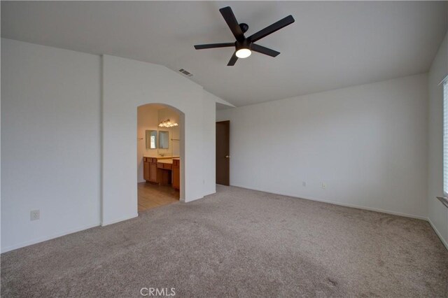 unfurnished bedroom with visible vents, arched walkways, lofted ceiling, and light carpet