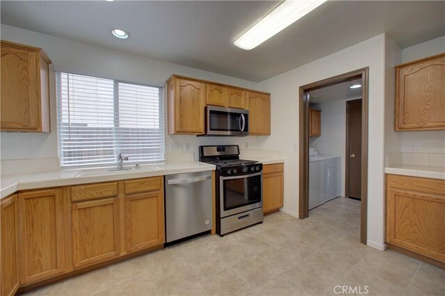 kitchen featuring recessed lighting, washer and clothes dryer, tile counters, a sink, and appliances with stainless steel finishes