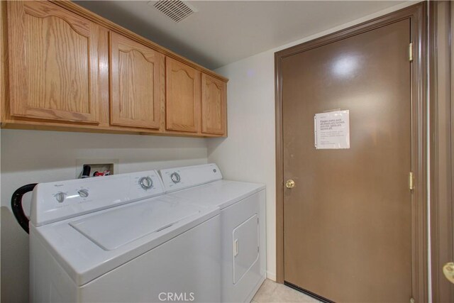 washroom with cabinet space, visible vents, and washing machine and dryer