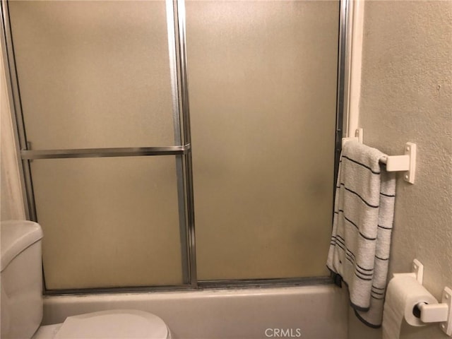 bathroom with shower / bath combination with glass door and toilet